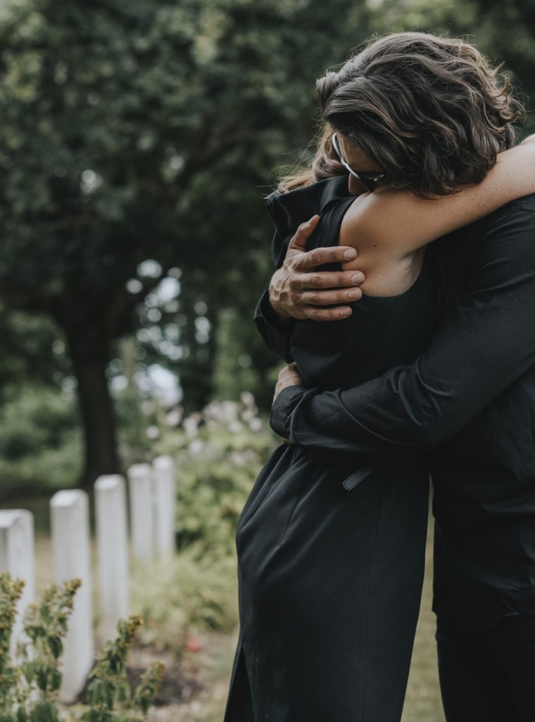 husband-trying-to-comfort-his-wife-at-a-graveyard.jpg husband-trying-to-comfort-his-wife-at-a-graveyard.jpg