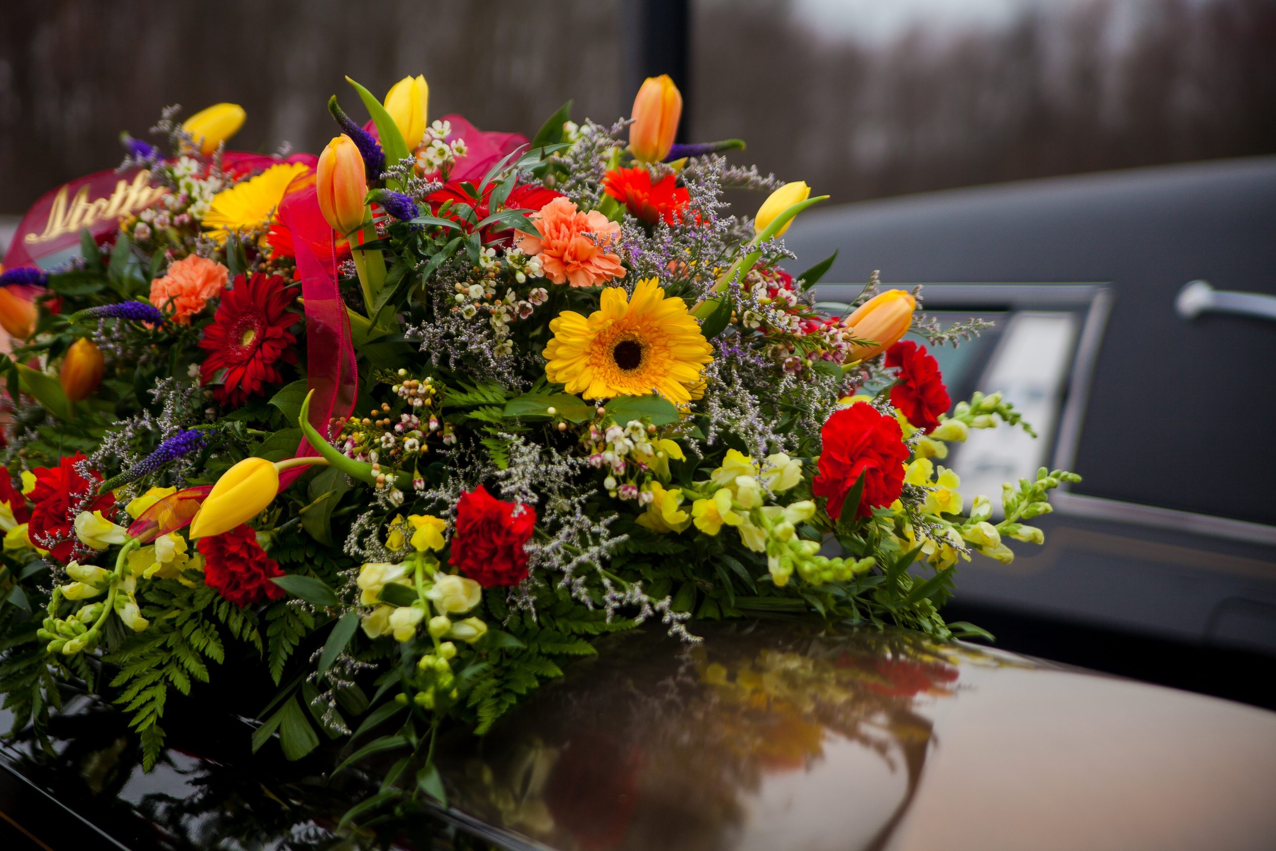 funeral-casket-and-flowers-next-to-hearse